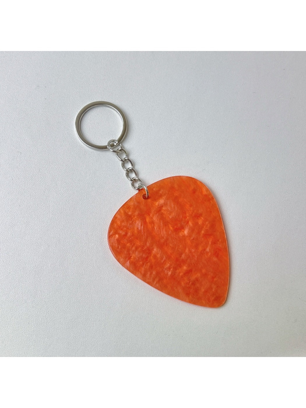 Silver textured teardrop charm keychain displayed with other metallic accessories
