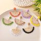 Close-up of Earedge raffia fan shaped drop earrings on white background