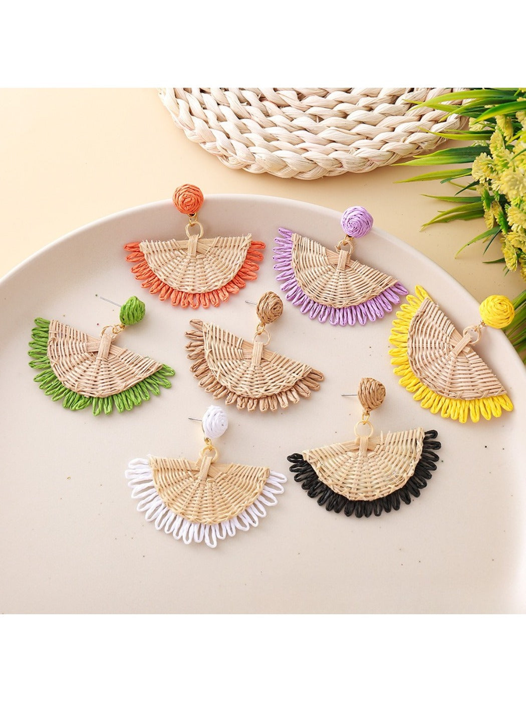 Close-up of Earedge raffia fan shaped drop earrings on white background