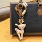 Deer charm keychain hanging from a backpack zipper in an outdoor setting