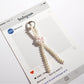 Keypus keychain featuring a handcrafted bow made of small pink and white beads