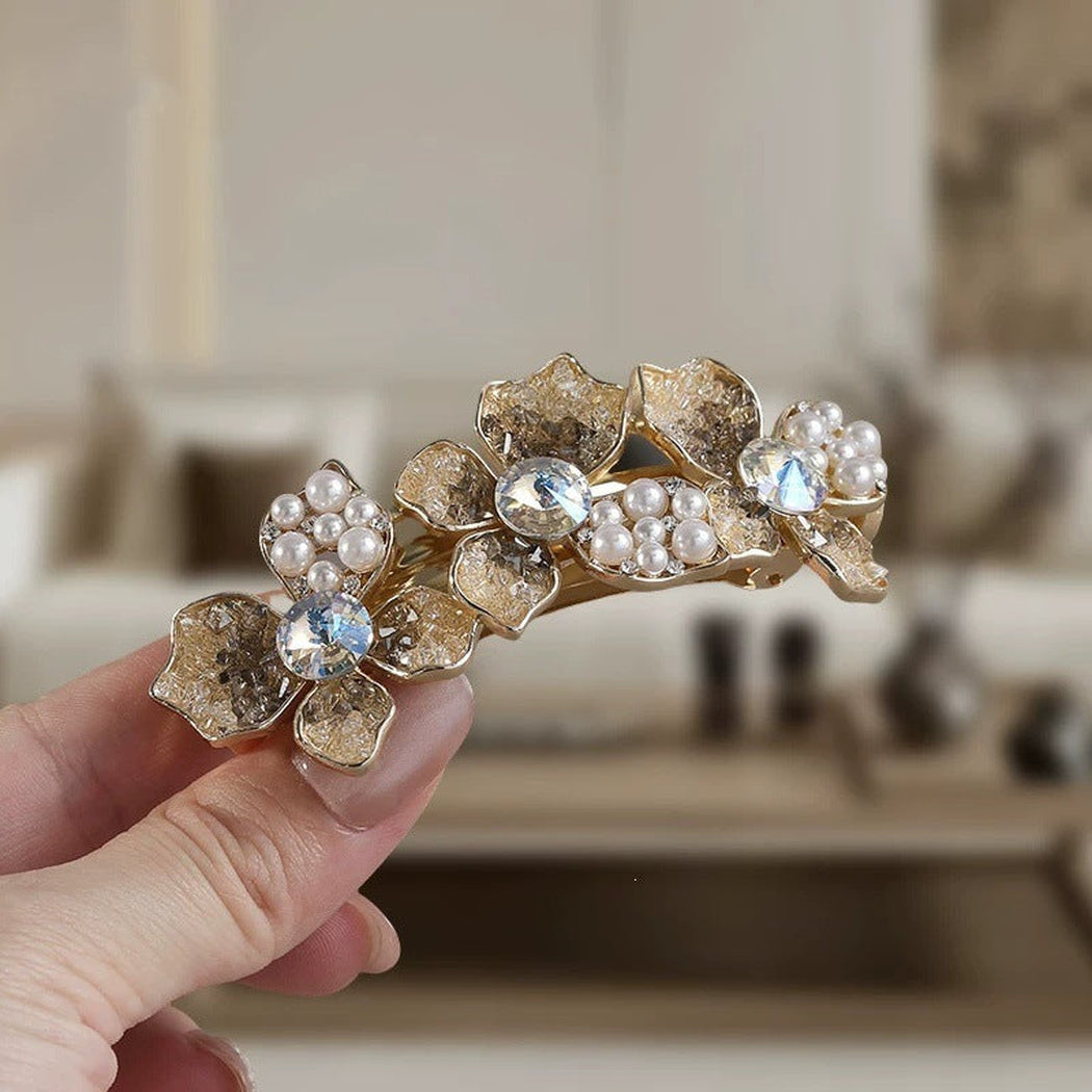 Gold-tone floral barrette held for a close view