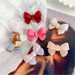 Beau delicate bow hair clip in soft pink fabric with gold accents on a white background