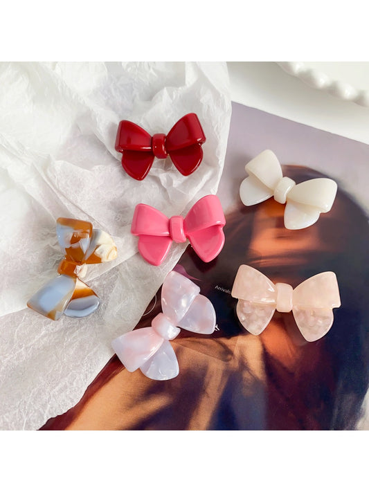 Beau delicate bow hair clip in soft pink fabric with gold accents on a white background