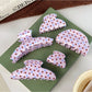Beau crescent shaped pink claw clip with white polka dots on a white background