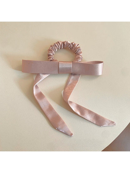 Close-up of a stylish hair tie with a large bow embellishment in soft pink fabric