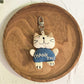 Cartoon cat keychain hanging from a bag zipper in natural light