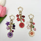 Close-up of delicate daisy charm on a gold keychain with a lobster clasp