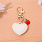 Heart shaped bag charm keychain displayed alongside matching red leather wallet