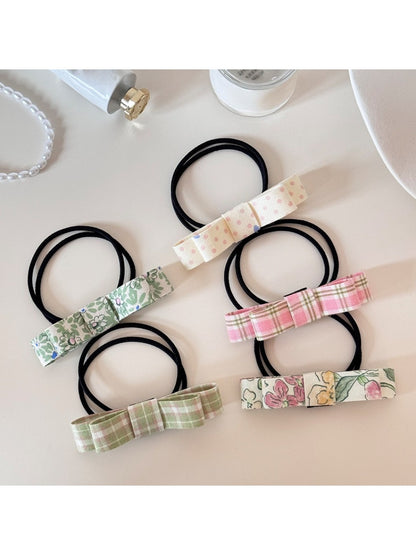Close-up of a cute hair tie with a pink bow embellishment on a white background