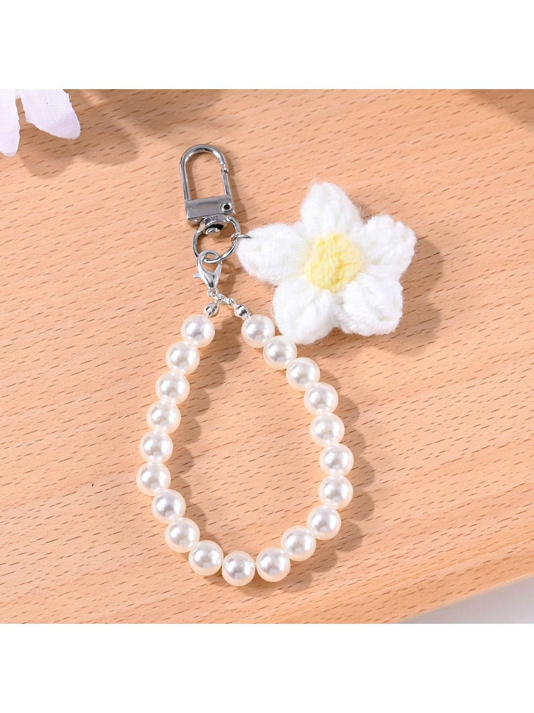 Top view of a multicolored yarn flower keychain with small beads attached to a keyring