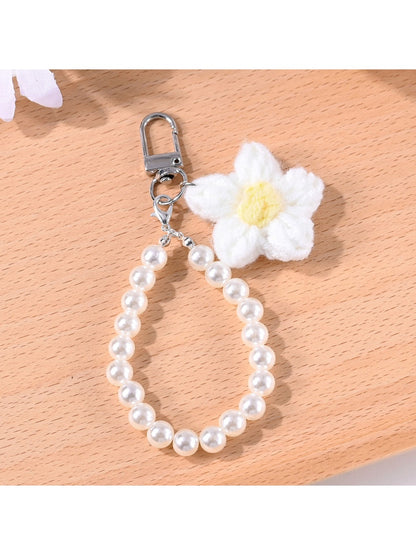 Top view of a multicolored yarn flower keychain with small beads attached to a keyring
