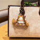 Vintage girl charm keychain next to a small gift box on a white background