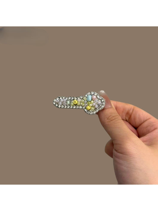 Close-up of Beau key shaped hair clip in gold metal finish