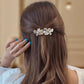 Gold-tone floral branch barrette worn in hair