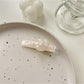 Beau hair clip placed on wooden surface with natural light highlighting colors