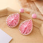 Earedge raffia teardrop earrings styled with summer accessories on a table