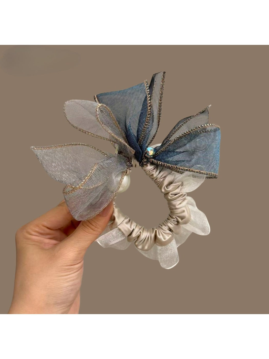 Hair tie with bow placed on a white surface with soft shadows