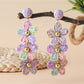 Earedge flower shaped raffia drop earrings displayed with green leaves background