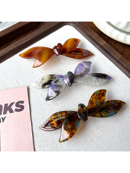 Beau bow shaped updo hair clip held in hand displaying size and shape