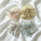 Gifty sheer tulle scrunchie with tiny pink and white floral pattern on a white background