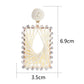 Earedge raffia square drop earrings hanging on a jewelry stand