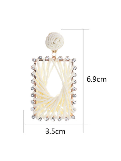 Earedge raffia square drop earrings hanging on a jewelry stand