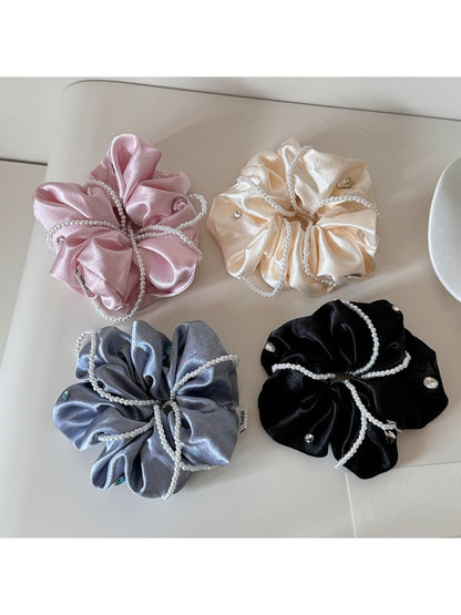Close-up of Gifty satin scrunchie in soft pink fabric with smooth texture