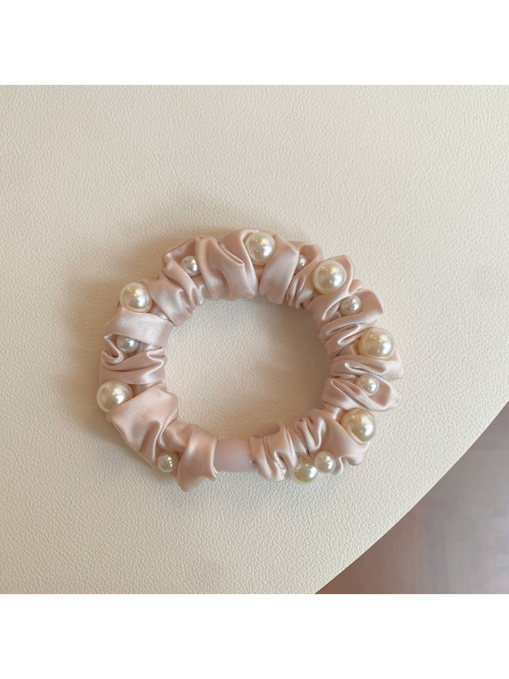 Pink mini scrunchie styled on a wrist as a bracelet accessory
