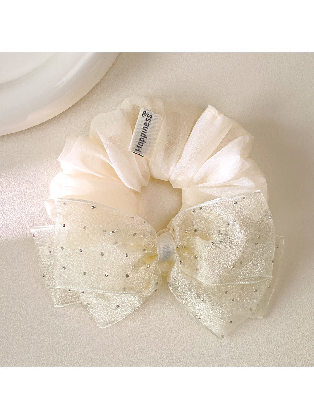 Pink tulle bow scrunchie displayed on a wooden surface