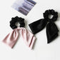 Top view of satin bow hair tie showing smooth fabric texture and tied bow