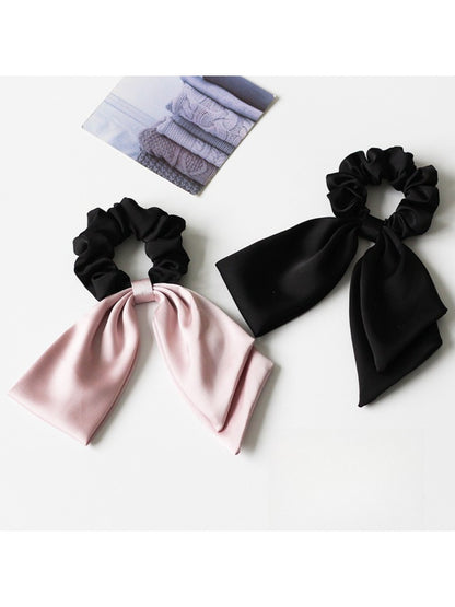 Top view of satin bow hair tie showing smooth fabric texture and tied bow