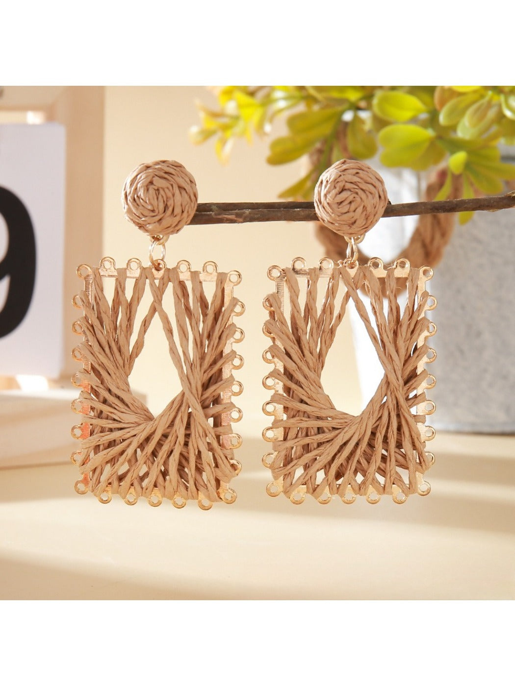 Earedge raffia wrapped square earrings displayed against a neutral fabric background