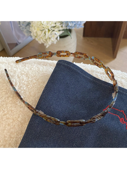 Close-up of Gifty acetate chain style headband showing glossy tortoiseshell links