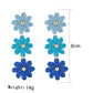 Colorful flower drop earrings hanging from a jewelry stand