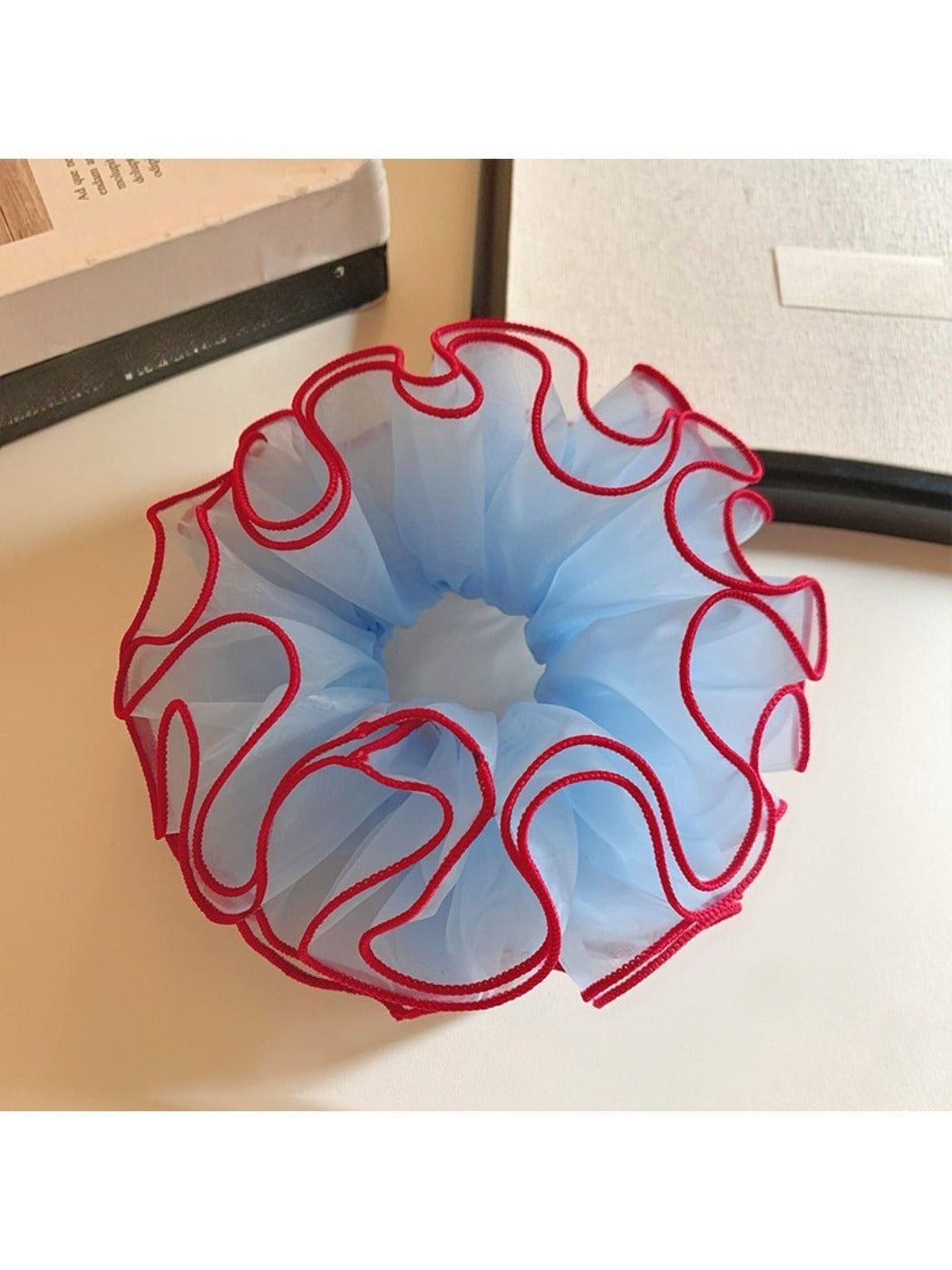 Blue tulle scrunchie with red trim displayed flat