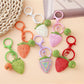 Close-up of a cute strawberry charm keychain with green leaves and red seeds