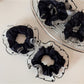 Black scrunchie with white polka dot trim on a white background