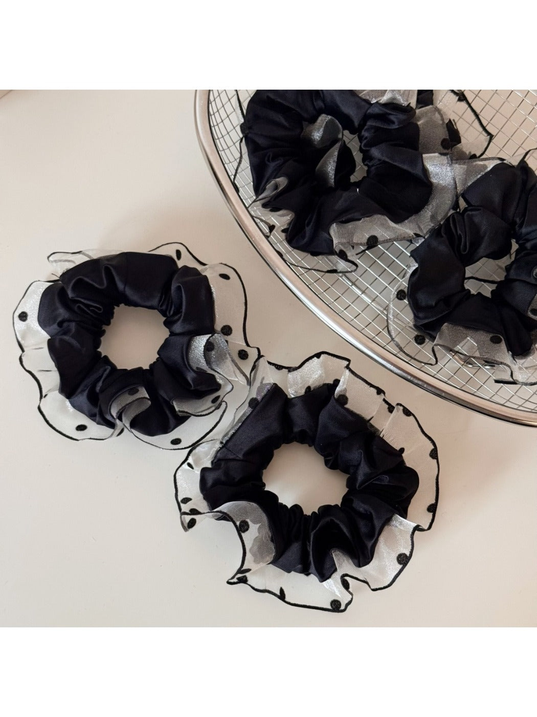 Black scrunchie with white polka dot trim on a white background