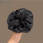 Vintage tulle scrunchie with white polka dots on beige fabric, styled on a wrist