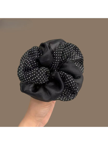 Vintage tulle scrunchie with white polka dots on beige fabric, styled on a wrist