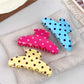 Beau polka dot half circle claw clip held in hand for size reference