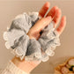 Minimalist gray fabric scrunchie with ruffle detail on a white background