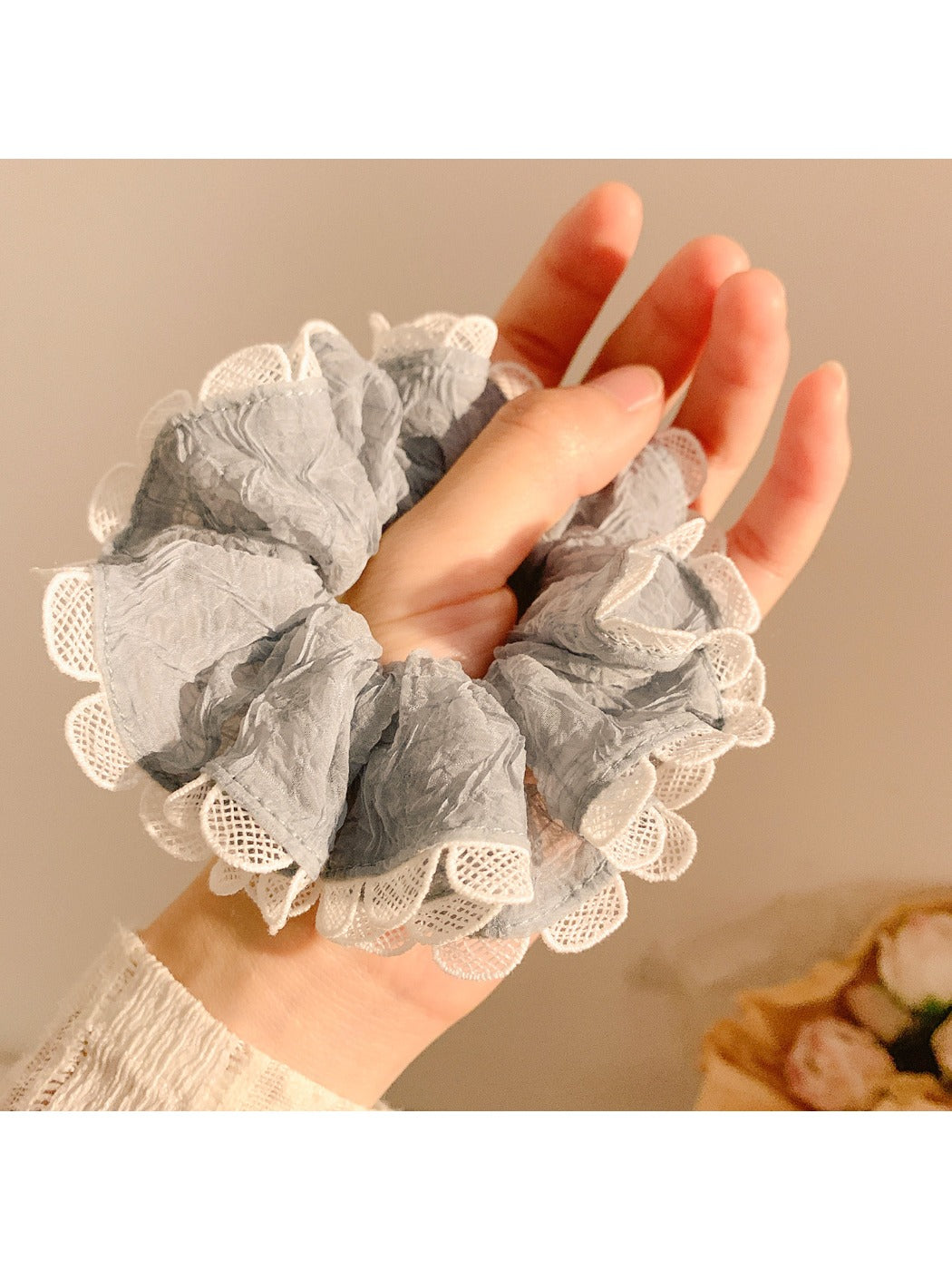 Minimalist gray fabric scrunchie with ruffle detail on a white background