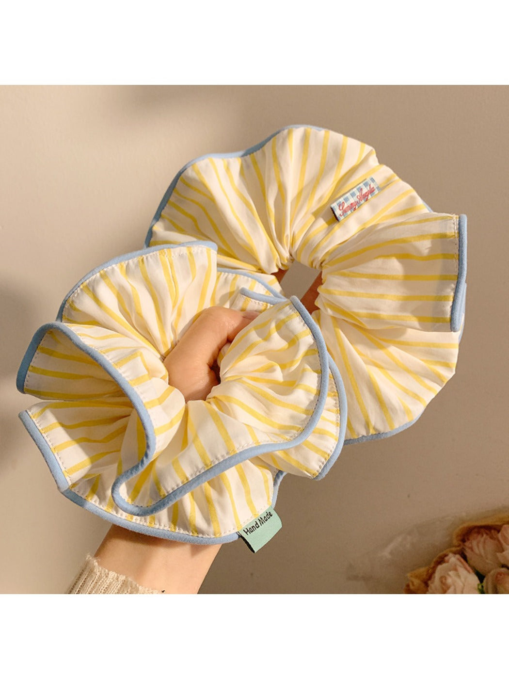 Chic yellow hair scrunchie with white stripes on a white background