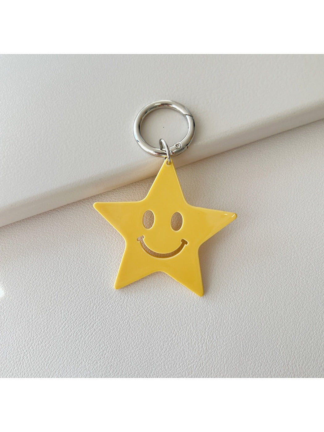Hand holding a silver star pendant keychain with a keyring attached