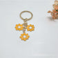 Peach blossom keychain hanging from a set of keys on a wooden surface