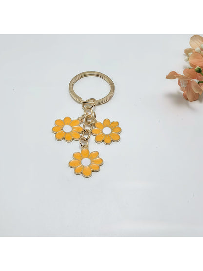 Peach blossom keychain hanging from a set of keys on a wooden surface