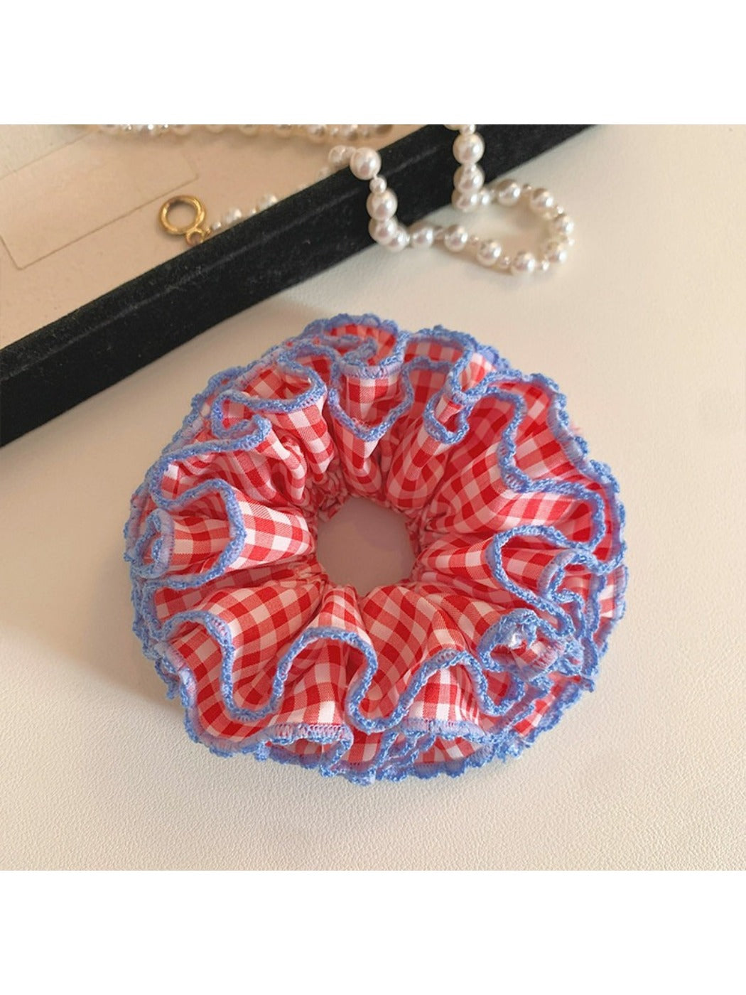 Red plaid ruffled scrunchie displayed flat highlighting its elastic band