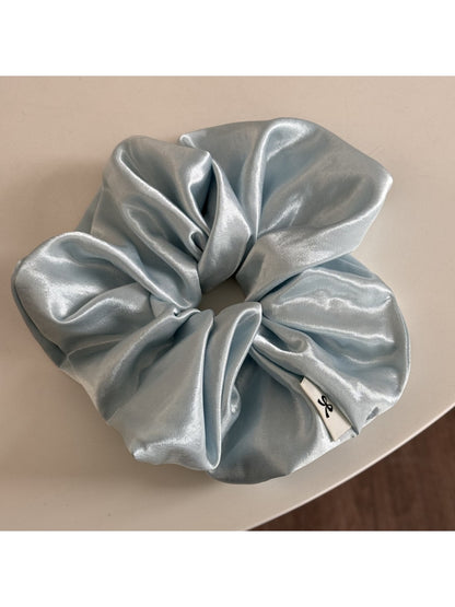 Glossy satin scrunchie in pink displayed flat showing elastic inside